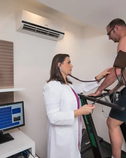 Médica acompanhando o teste ergométrico de um paciente na esteira